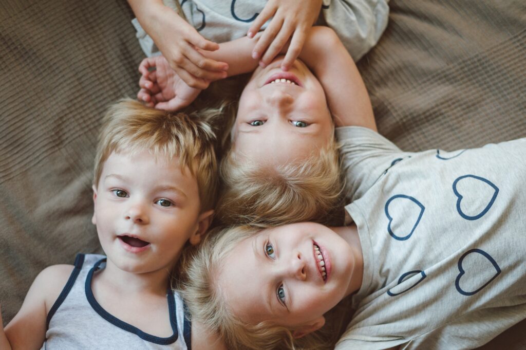 portrait of three smiling children lying on the bed, close-up
