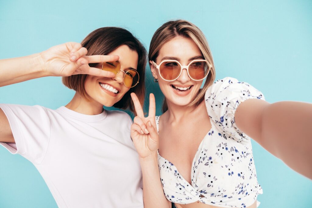 Two young beautiful smiling women posing in studio
